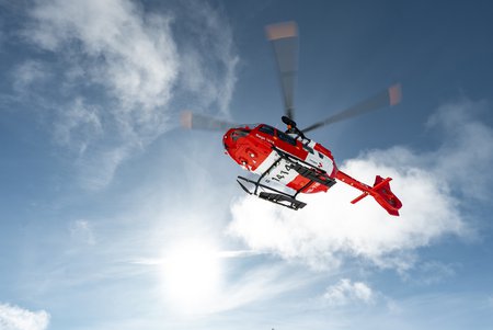 Zum Downloadformular für das Bild Rega-Helikopter im Flug, von unten gegen den blauen Himmel fotografiert.