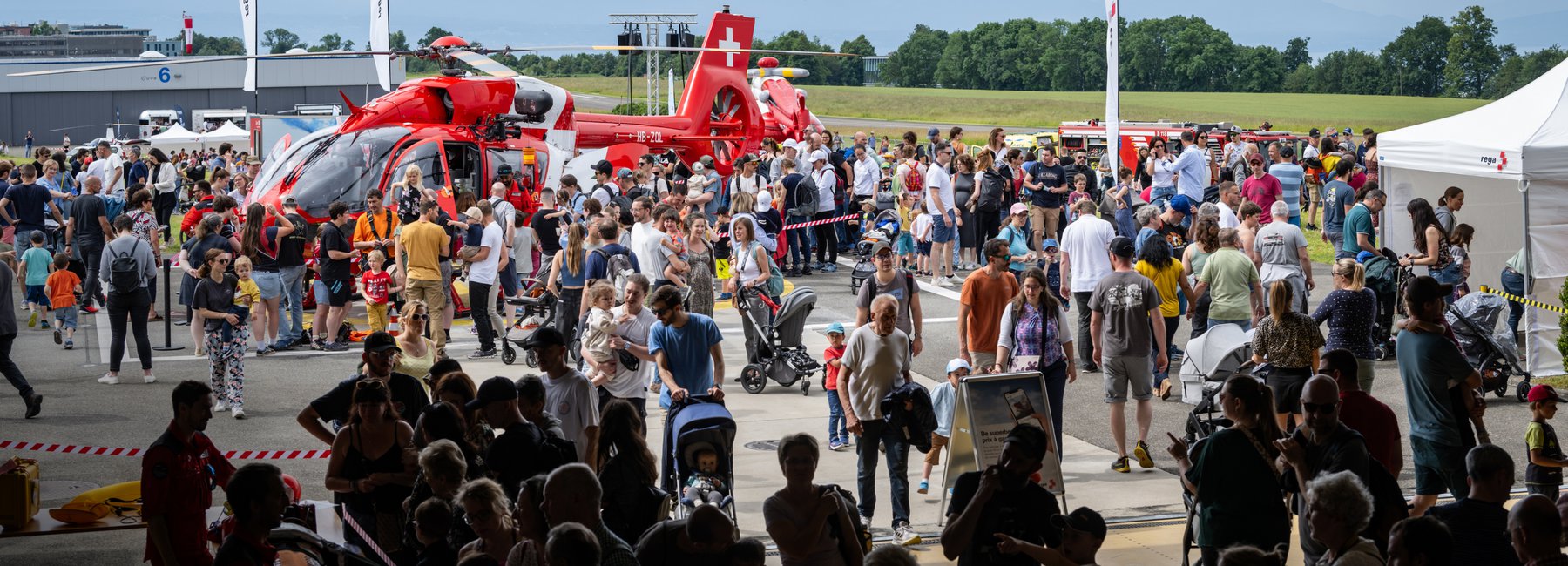 Eine grosse Menschenmenge steht um einen Rega-Helikopter auf einem Flugfeld. Das Bild stammt von einem Tag der offenen Tür.