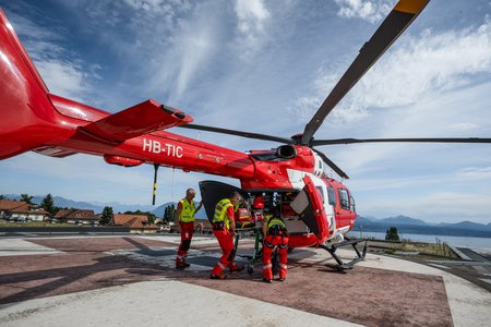 Zum Downloadformular für das Bild Rega-Crew auf dem Landeplatz eines Spitaldachs vor der Übergabe der Patientin.