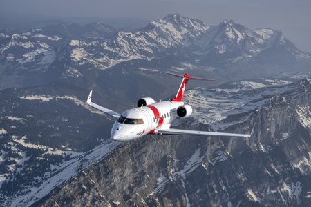 Zum Downloadformular für das Bild Rega-Ambulanzjet im Flug über eine alpine Berglandschaft.