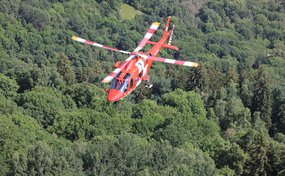 Elicottero Rega in volo sopra un fitto bosco