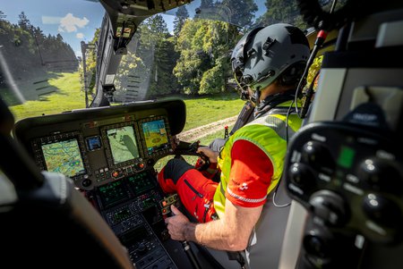 Zum Downloadformular für das Bild Blick ins Cockpit eines Rega-Helikopters mit Pilot während des Fluges.