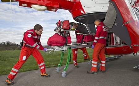 Die Rega-Crew lädt die neue Roll-in-Trage in den EC 145-Helikopter